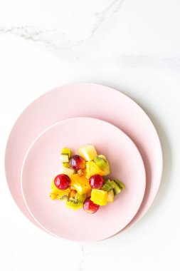 Pembe tabakta taze organik meyve salatası, sağlıklı beslenme ve detoks diyet planı.