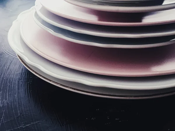 Stack med rena tomma tallrikar på svart bakgrund, bestick och bordsdekoration — Stockfoto