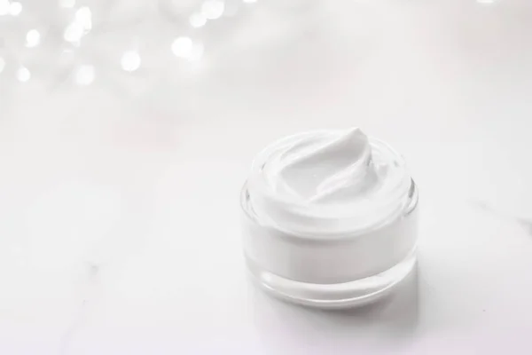 Facial cream moisturizer jar on holiday glitter background, anti-age skin care product