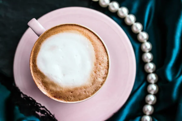 Cangkir cappuccino dan perhiasan mutiara pada kain sutra, kafe mewah — Stok Foto
