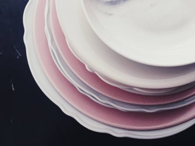 Siyah zemin üzerinde temiz boş tabak yığını, lüks bulaşık takımı ve masa dekoru