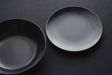 Siyah arka planda boş tabaklar, bayram yemeği için kaliteli bulaşık takımı, minimal tasarım ve diyet