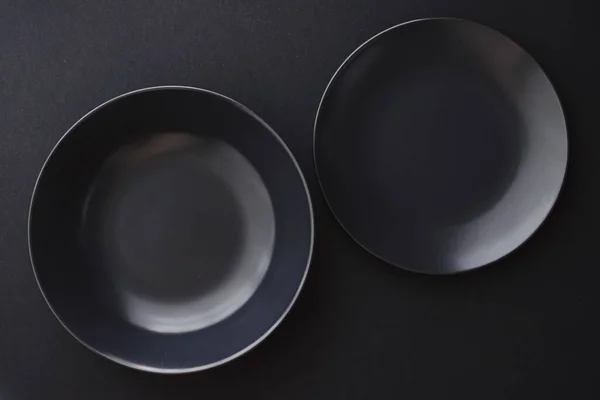 Assiettes vides sur fond noir, vaisselle haut de gamme pour le dîner de vacances, design minimaliste et régime alimentaire — Photo
