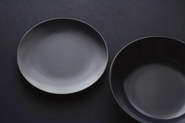 Platos vacíos sobre fondo negro, vajilla premium para la cena de vacaciones, diseño minimalista y dieta — Foto de Stock