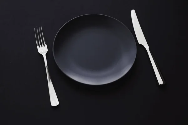 Pratos vazios e talheres em fundo preto, talheres premium para jantar de férias, design minimalista e dieta — Fotografia de Stock