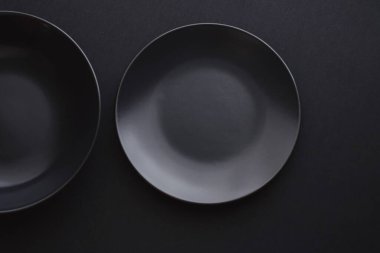 Siyah arka planda boş tabaklar, bayram yemeği için kaliteli bulaşık takımı, minimal tasarım ve diyet