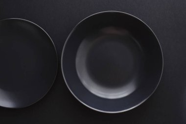 Siyah arka planda boş tabaklar, bayram yemeği için kaliteli bulaşık takımı, minimal tasarım ve diyet