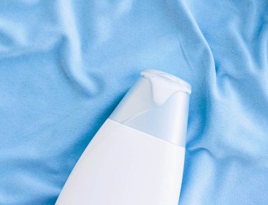 Mavi ipek arka planda boş etiket şampuan şişesi veya duş jeli modeli, güzellik ürünü ve vücut bakımı kozmetiği