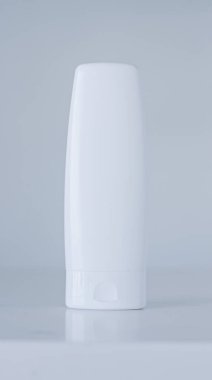 Gri arka planda ürün modeli olarak boş etiket kozmetik kutu şişesi