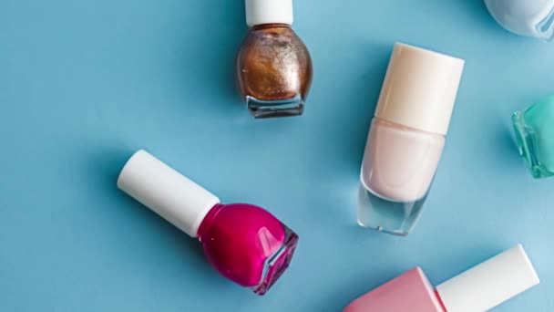 Botellas de esmalte de uñas sobre fondo azul, cosméticos de belleza y maquillaje — Vídeos de Stock