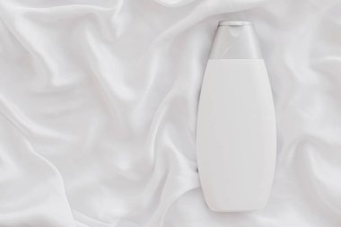 Beyaz ipek arka planda ürün modeli olarak boş etiket kozmetik kutu şişesi