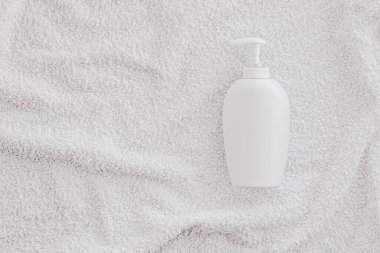 Beyaz havlu arka planında ürün modeli olarak boş etiket kozmetik kutu şişesi