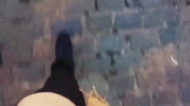 Siyah ayakkabılı bir kadın eski kaldırım yolunda yürüyor