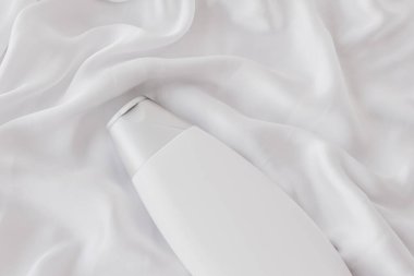 Beyaz ipek arka planda ürün modeli olarak boş etiket kozmetik kutu şişesi