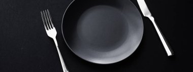 Siyah arka planda boş tabaklar ve gümüş takımlar, bayram yemeği için özel sofra takımı, minimal tasarım ve diyet