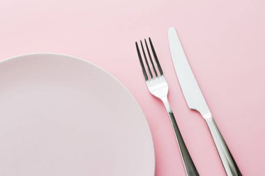 Boş tabak ve çatal bıçak seti pembe arka planda, en iyi sofra takımı şef masa dekorasyonu ve menü markalaşması için