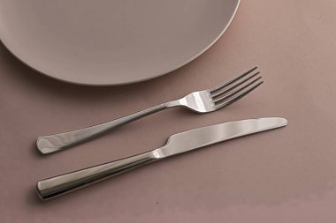 Boş tabak ve çatal bıçak seti kahverengi arka planda, şef masa dekorasyonu ve menü markalaşması için en üst masa takımı