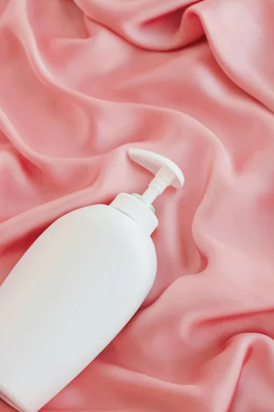 Frasco de recipiente cosmético de etiqueta em branco como maquete de produto em fundo de seda rosa — Fotografia de Stock