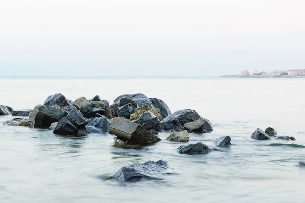 De stenen op het strand onder de binnenkomende golf — Stockfoto