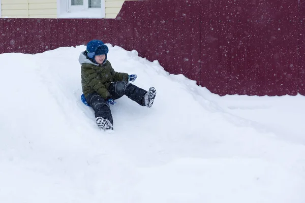 雪のスライドとそり滑り少年 — ストック写真