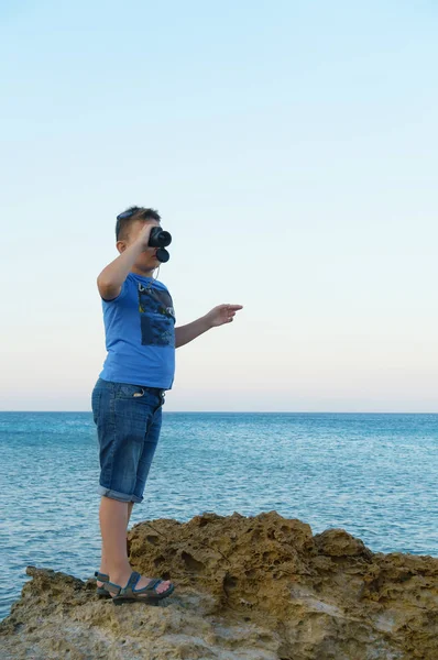 Chłopiec patrzy przez teleskop na błękitne morze — Zdjęcie stockowe