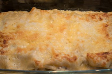 Masanın üzerinde fırında taze lazanya olan cam mutfak kabı.