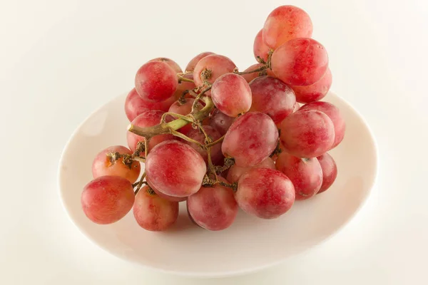 一束新鲜的葡萄放在白背石上的餐盘上 — 图库照片