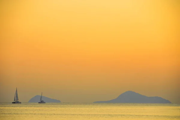 Sailboat in the distance under the setting sun near Santorini, Greece — Stock Photo, Image