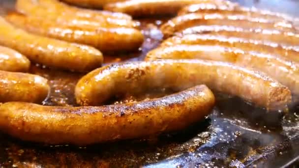 Sausages frying on a large open griddle — Stock Video