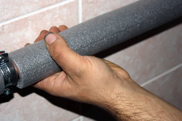 Worker cuts the foam insulation for pipes