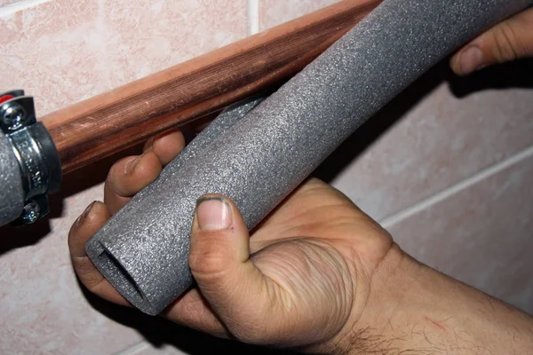 Worker cuts the foam insulation for pipes