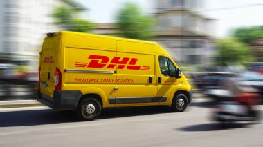 MILANO, ITALY - 24 Nisan 2018: sarı bir DHL kurye servis aracı Milano 'da sokağa teslimat için acele ediyor. DHL 'nin sahibi Alman posta servisi Deutsche Post..