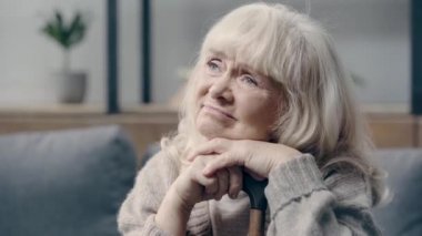 Bunamış yaşlı bir kadın elinde baston tutuyor.