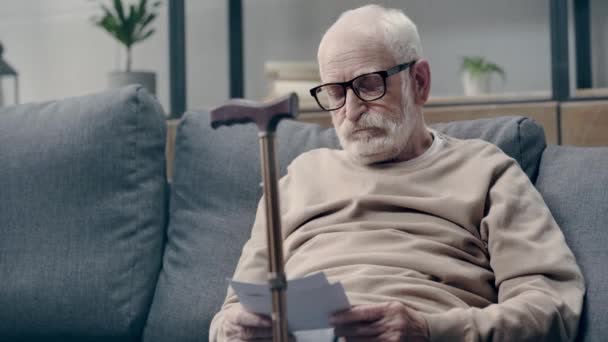 Demenzkranker Senior Schaut Sich Fotos Auf Sofa — Stockvideo