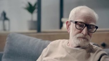 Bunamış yaşlı bir adam telefonda konuşuyor.