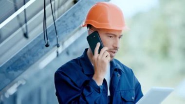 Mühendis, güneş pili yakınında akıllı telefondan konuşuyor. 