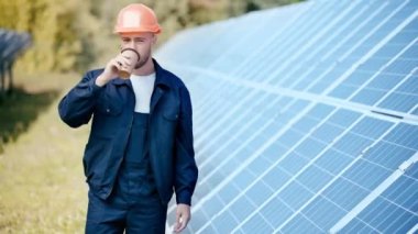 Mühendis kahve içiyor ve kameraya bakıyor. 