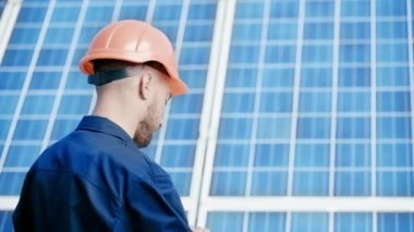 Makinist kameraya bakıyor ve kaska dokunuyor. 