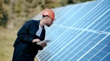 Alet kullanan ve güneş paneline bakan mühendis. 