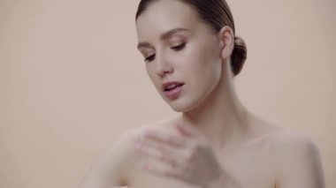 Yüz temeli uygulayan kadın bej üzerine izole edilmiş 