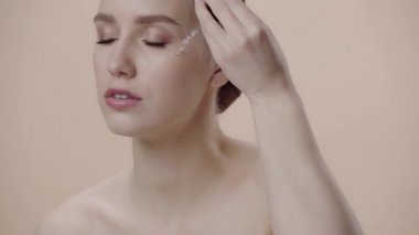 Bej üzerine izole serumu uygulayan çekici bir kadın. 