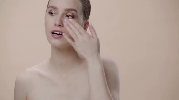 Mulher Atraente Aplicando Creme Facial Isolado Bege — Vídeo de Stock