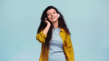 Neşeli kız dans ediyor ve mavi renkte müzik dinliyor. 