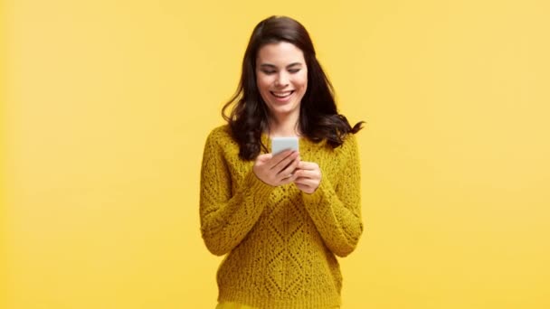 Süveter Giyen Gülümseyen Kız Sarı Renkte Izole Akıllı Telefondan Mesaj — Stok video