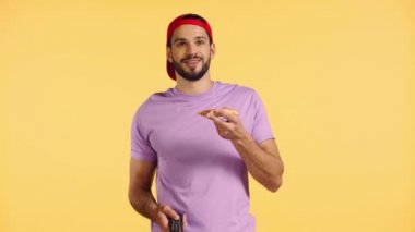 Sarı üzerine izole edilmiş televizyon izleyen gülümseyen adam 