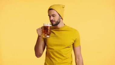 Gülümseyen adam sarıda bira içiyor.