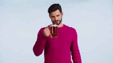 Gülümseyen adam mavi üzerinde bira içiyor. 