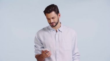 Mavi üzerine izole akıllı telefonu işaret eden gülümseyen adam. 