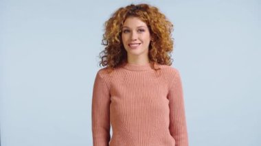 Gülümseyen kadın kameraya bakıyor ve gri renkte başını sallıyor.