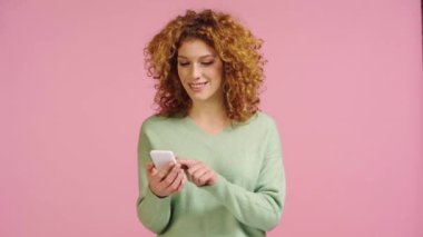 Pembe ekranda yeşil ekranlı akıllı telefon gösteren pozitif kadın